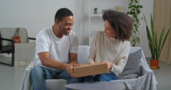 Afro American Couple Receiving Parcel at Home During Lockdown Pull in Different Directions Cardboard alt