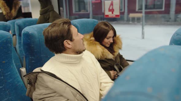 A Couple of Average People Take Off Their Outerwear in Their Seats in the Train Car