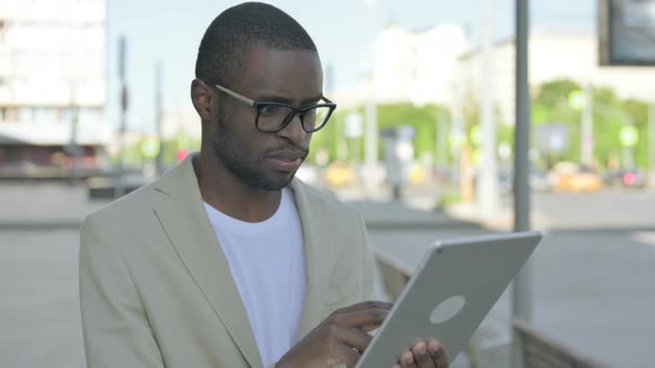 Upset African Man Reacting to Loss on Tablet Outdoor alt