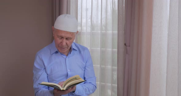 An Old Muslim Man Reading Koran at Home