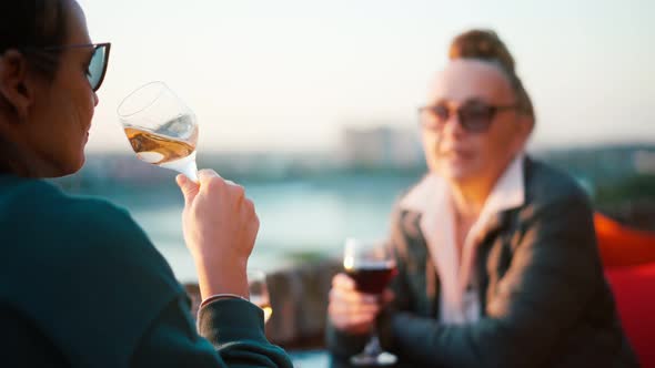 Mature Woman in Glasses Sitting in a Cafe with Her Daughter and Drinking Wine alt