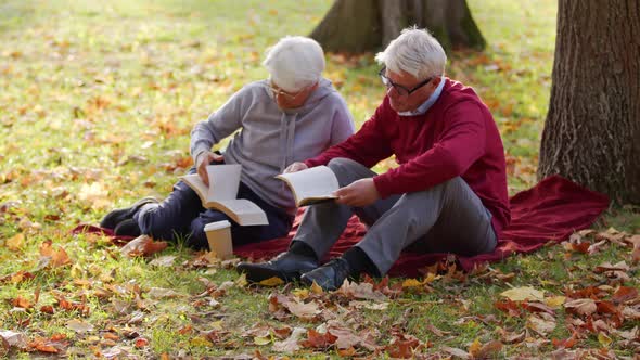 Senior Caucasian Married Couple Read Together on the Ground in the Park Full Shot Selective Focus alt