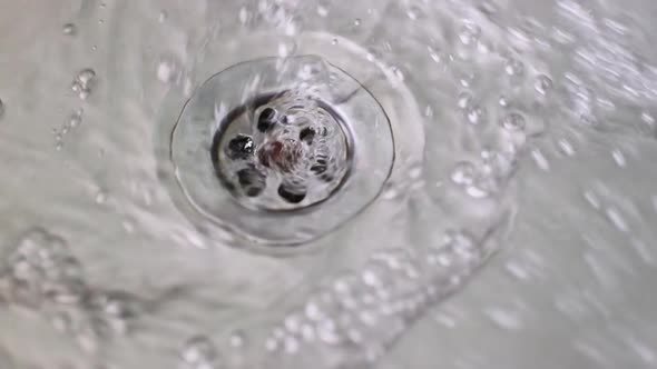 Water Drains Into the Hole of a Stainless Steel Sink Close Up