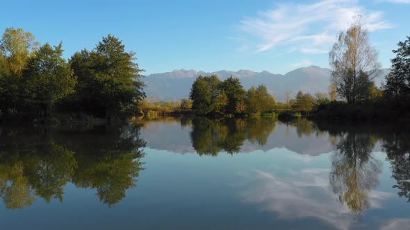 Lake at the edge of the mountains with forest reflected in the clear water. Idylic autumn landscape alt