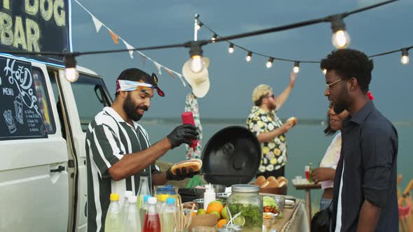 Food Truck Seller Cooking Hot Dogs and Speaking with Customers alt