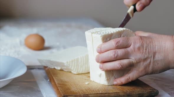 Close-up Female Hands Is Cutting a Cheese for Bakery Preparation