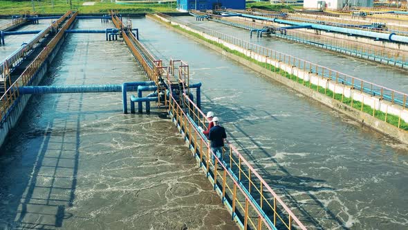 Two Businessmen Walking Through a Large Wastewater Cleaning Facility alt