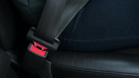 Hand of a driver girl who fastens herself with a seat belt of a car alt