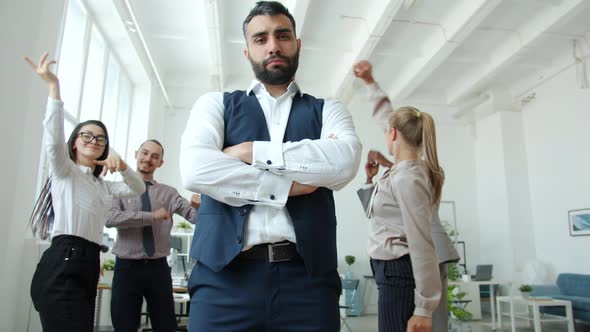 Low Angle View of Serious Business Owner Standing at Corporate Event While People Dancing alt