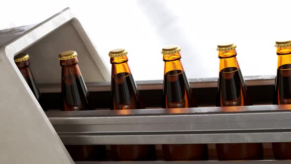 Glass bottles with liquid inside moving gradually in a factory pipeline. 4KHD alt