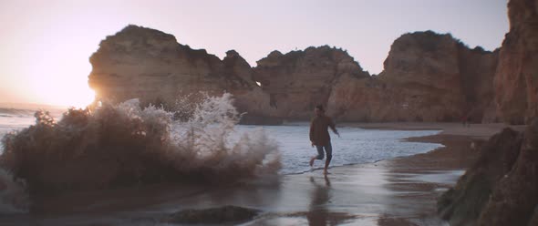 A young man playing with his dog on a wild beach alt