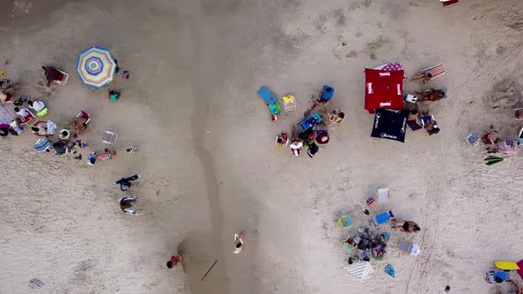 Aerial top down shot of people enjoying on a crowded beach in Brazil. Dolly right alt
