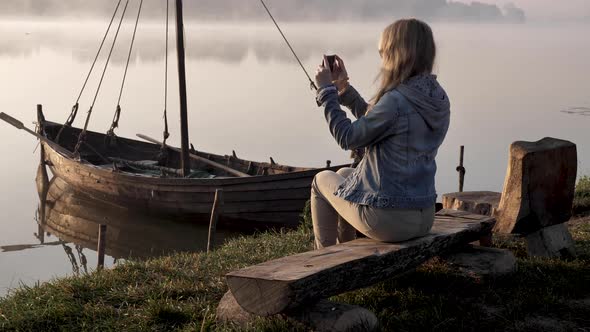 Woman Filming A Boat On A Smartphone alt
