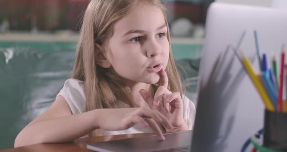 Close-up Face of Caucasian Girl Looking at Laptop Screen and Using Touchpad. Education, E-learning alt
