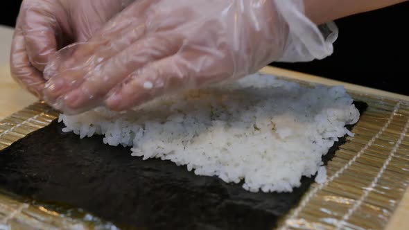 Closeup of a Sushi Chef's Hands are Preparing a Roll