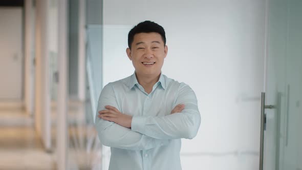 Successful Middle Aged Asian Businessman Posing at Office Building Crossing Hands and Smiling to alt