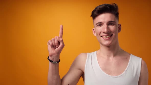 Young Man Pointing to Copy Space for Advert Yellow Background