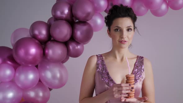 Woman in a Purple Dress Stands on the Background of Balloons alt