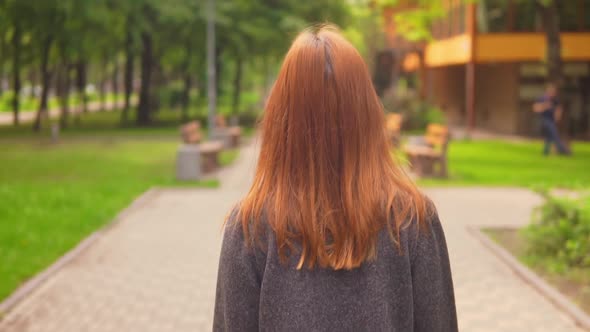 Close Up Redheaded Businesswoman Walking Along the Alley alt