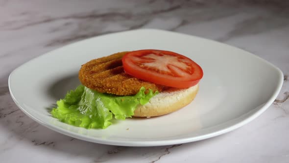 Process of Assembling a Fish Burger on a White Plate