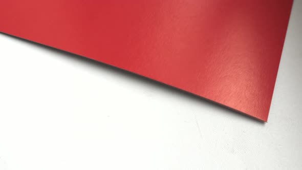 4k video, close-up, one sheet of red paper rotating on a white background, top view