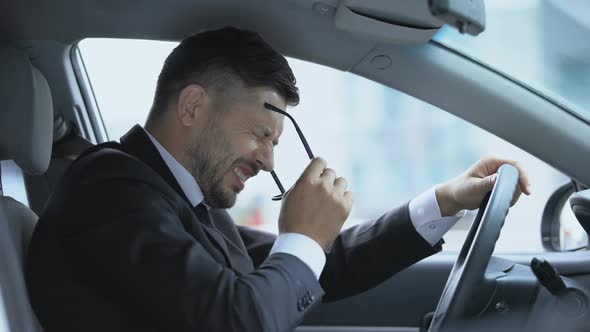 Car Driver Taking Off Glasses and Leaning on Steering Wheel Feeling Headache