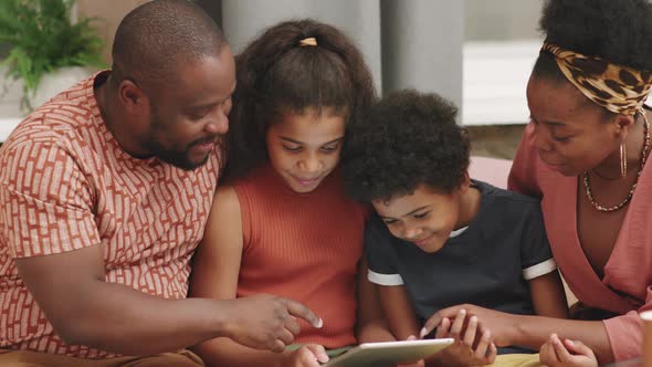 Afro Family Of Four Playing Games On Digital Tablet alt