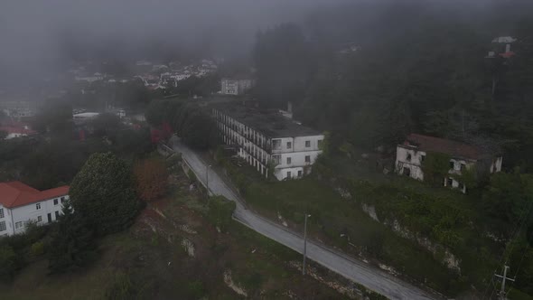 Aerial drone view over Caramulo Sanatorium old abandoned building on misty day, Portugal alt