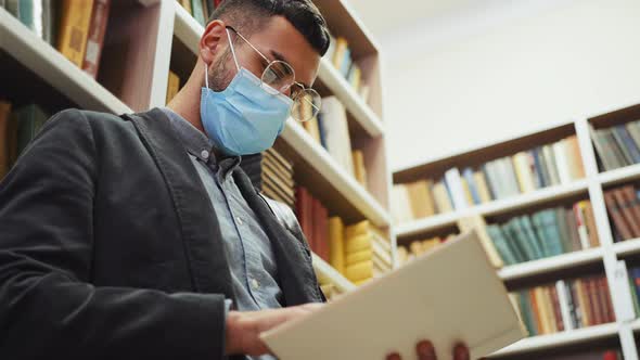 Man in Mask Reading Book in Book Shop alt