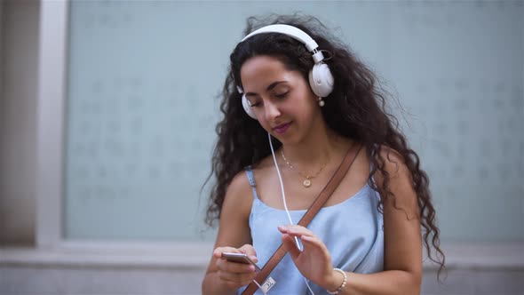 Happy Young Woman Listening To Music on Smartphone and Dancing