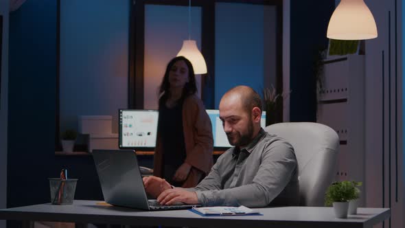 Exhausted Businessman Checking Marketing Statistics on Laptop Computer alt