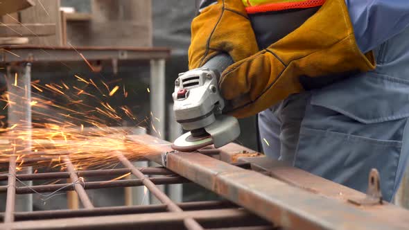 Welder man using angle grinder while working in industrial workshop. Sparks during the cutting  alt