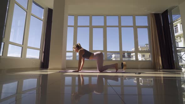 Slim Woman Does Sports Exercises Near Large Panoramic Window