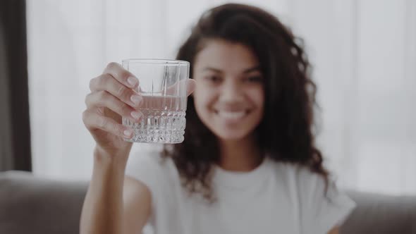 Smiling Young African Woman Holding Glass of Fresh Clear Purified Potable Water Offer to Drink alt