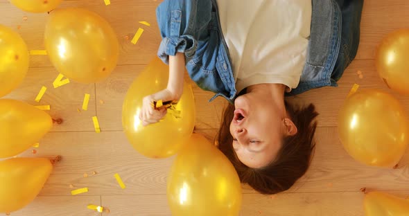 happy young woman at birthday party smiling and having fun of lying on the floor with gold 