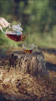 Woman pours tea from a glass teapot into a glass Cup