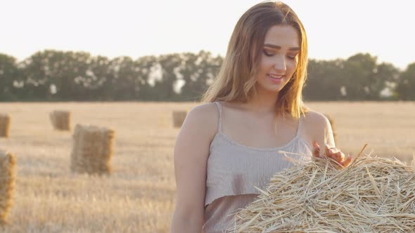 beautiful girl leaned on haystack relaxing in field, leisure and lifestyle