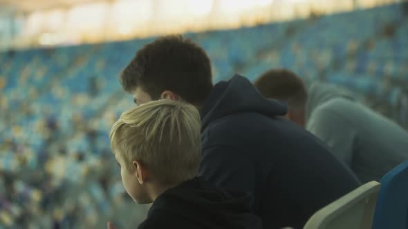 Older Brother Explaining Rules of Sport Game to Boy at Stadium, Brotherhood alt