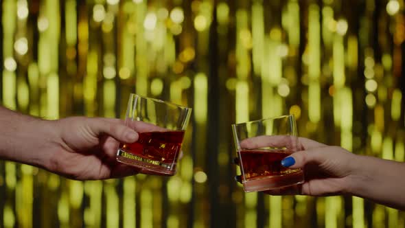Two Hands with Glasses of Cognac Whiskey with Ice Cubes Making Cheers Raising Toast Celebrating alt