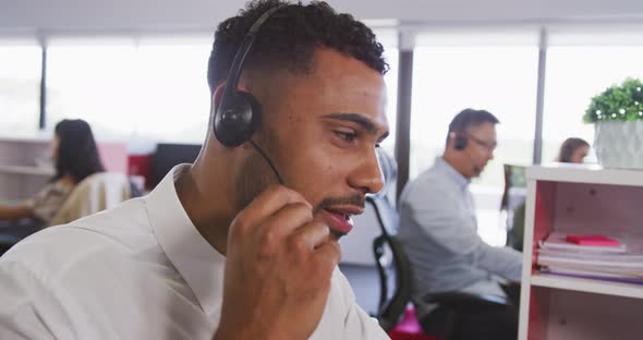 Professional businessman smiling while talking on phone headset in modern office in slow motion alt