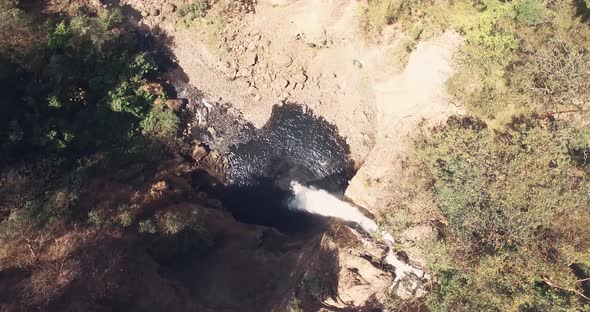 Drone footage rotating and closing up from top of big waterfall alt