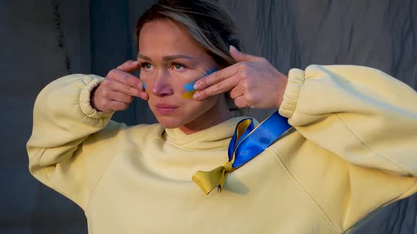 War Portrait of Ukrainian Woman with National Flag on Cheek Crying alt