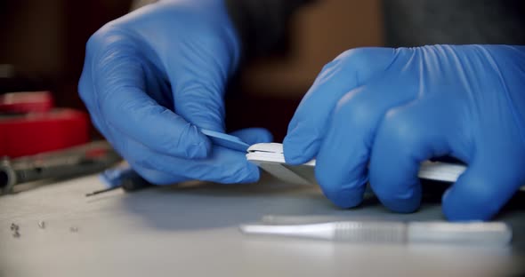 Repairman in Electronics Repair Service Using Special Tools Opens the Phone for Repair Close Up alt