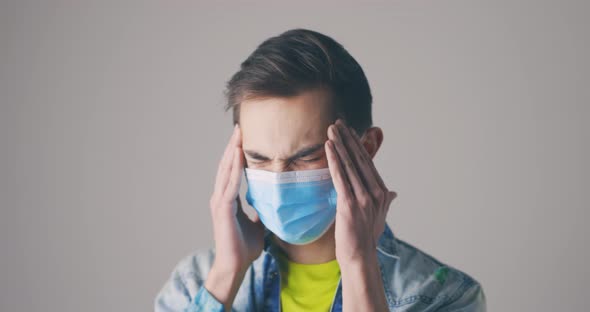 Man with Protective Medical Mask Rubbing Temples alt