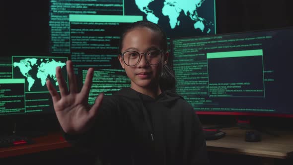 Young Girl Hacker With Multiple Computer Screens And Looking At Camera During Showing Stop Hand alt