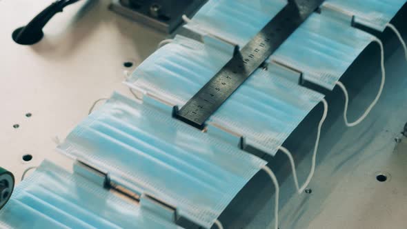 Face Masks Are Moving Along the Conveyor Under a Ruler alt