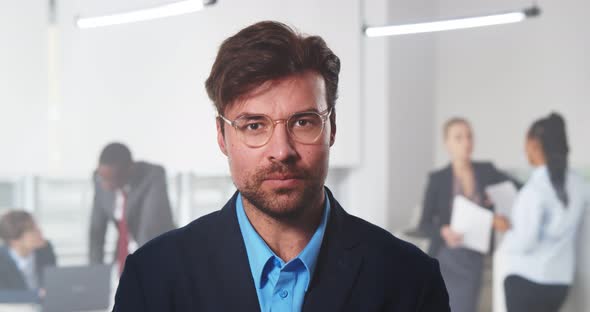 Handsome Young Businessman Standing in Office in Front of His Team alt