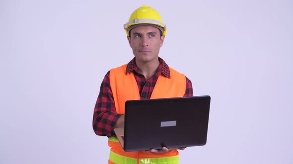 Young Happy Hispanic Man Construction Worker Thinking While Using Laptop