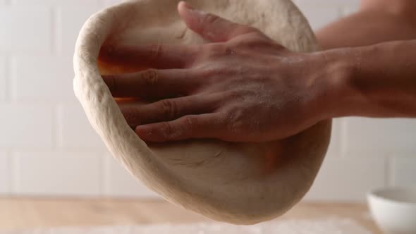 Camera follows man’s hands flattening a dough. Slow Motion. alt
