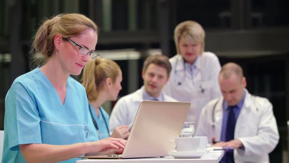 Nurse using laptop in conference room alt